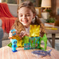 A young child plays with the MAGNATILES Shark Dive 13-Piece Set, which features colorful magnetic tiles, a blue figurine, and a toy shark on a table in the living room, creating an imaginative underwater play scene.