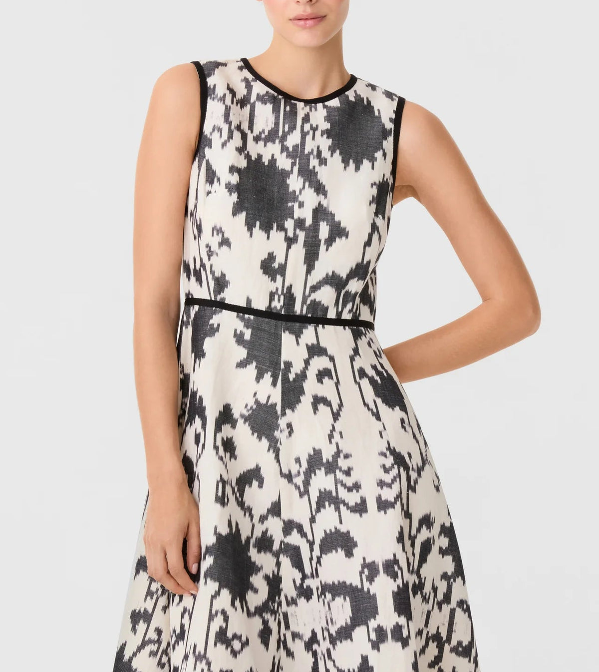 Emporio Sirenuse Clodette Ikat Blossom Dress, a sleeveless handloomed linen-cotton dress in a black and white ikat blossom print with black trim at the neck, armholes, and waist.