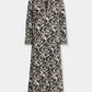 Emporio Sirenuse Giada Lotus Flower Dress, a long-sleeved midi caftan in cotton voile featuring a black and cream botanical floral pattern, a notched neckline, and banded cuffs.