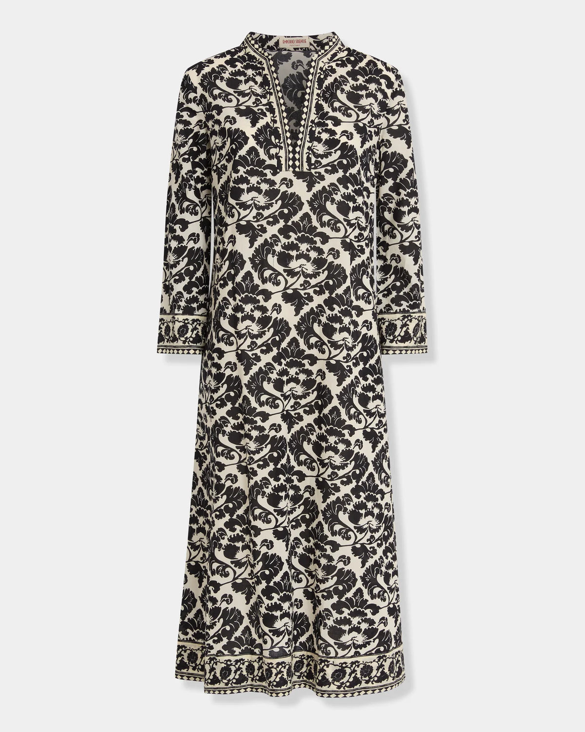 Emporio Sirenuse Giada Lotus Flower Dress, a long-sleeved midi caftan in cotton voile featuring a black and cream botanical floral pattern, a notched neckline, and banded cuffs.