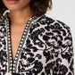 Close-up of an Emporio Sirenuse Giada Lotus Flower Dress in a black and cream print, featuring a V-neckline and geometric diamond-print trim.