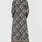 Back view of a person wearing a black and white lotus flower print Giada Lotus Flower Dress, featuring long sleeves and decorative trim at the neckline and hem.