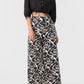 A model wearing a black cropped button-up shirt and Emporio Sirenuse Adele Lotus Flower Pants.