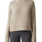 The person is wearing Lisa Yang's Sony Cashmere Sweater in beige, featuring fisherman ribbed trims, paired with grey trousers.