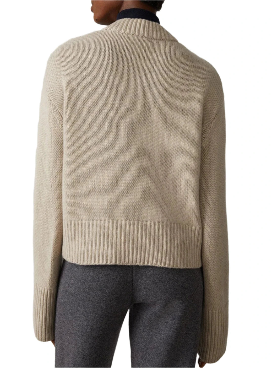 A person is seen from behind wearing the Lisa Yang Sony Cashmere Sweater, featuring a ribbed collar and hem in beige, paired with grey pants.