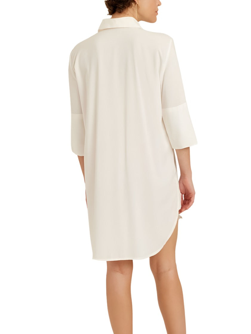 A person wearing a Lenny Niemeyer Chemisier Basic Dress, a classic fit, white long-sleeved collared tunic made from 100% viscose, stands with their back facing the camera, showcasing a timeless piece by Lenny Niemeyer.