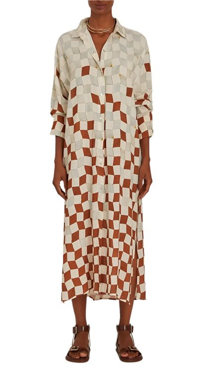 A person wearing the Lenny Niemeyer Comfort Button Up Shirt Dress, featuring geometric shapes in white and brown reminiscent of a Casablanca print, paired with sandals.