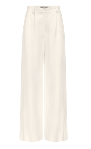 The Taite Pant by TWP features white wide-leg 100% linen trousers with a high waist, front pleats, belt loops, and zip fly closure, shown on a plain background.