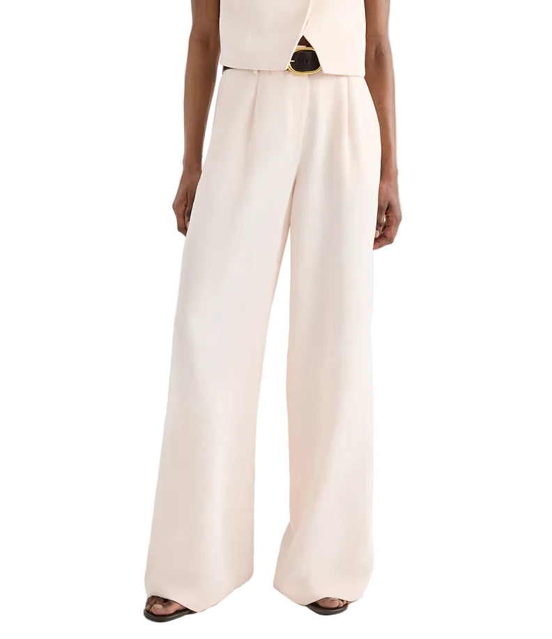 Wearing the TWP Hudson St Pant, styled in a high-waisted wide-leg silhouette with a matching sleeveless top and sandals, the person stands against a plain background.