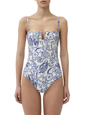 A woman wears the Simkhai Ottilie Strapless One Piece, featuring blue sea life prints, a charming seashell motif, and a notched neckline.