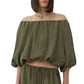 A woman wears the Simkhai Anni Puff Sleeve Cropped Top, an off-the-shoulder, loose-fit olive green blouse in lightweight crinkled fabric, paired with matching drawstring pants against a white background.