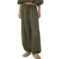 Model wears the Simkhai Freya Parachute Pant, featuring a loose fit, olive green hue, drawstring waist, and elastic cuffs, styled with a coordinating top and beige sandals.
