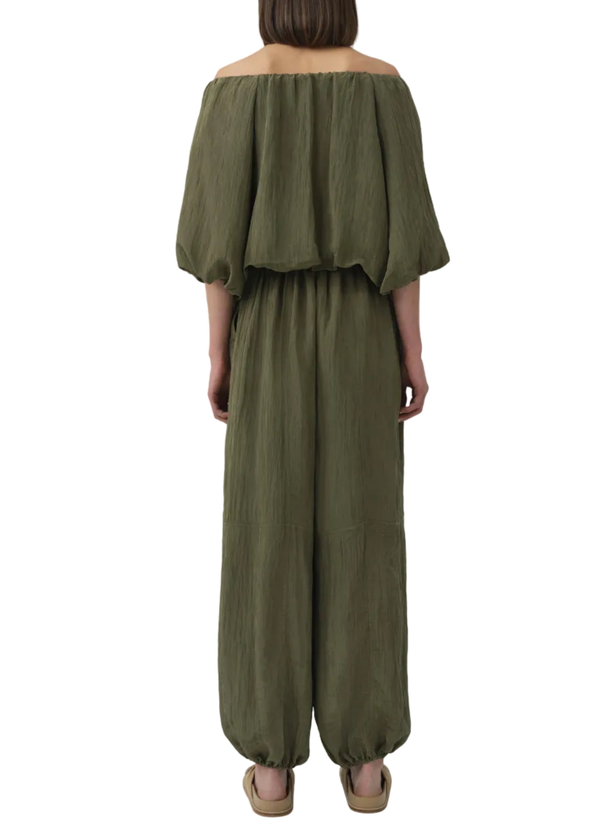 A person viewed from the back wears the Simkhai Freya Parachute Pant in olive green, featuring a drawstring waistband and elasticized ankles.