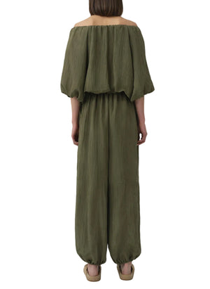 A person viewed from the back wears the Simkhai Freya Parachute Pant in olive green, featuring a drawstring waistband and elasticized ankles.