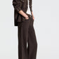 A person wearing a dark brown button-down shirt and matching dark chocolate TWP Harvest Moon Jean wide-leg jeans with a black belt and sandals.