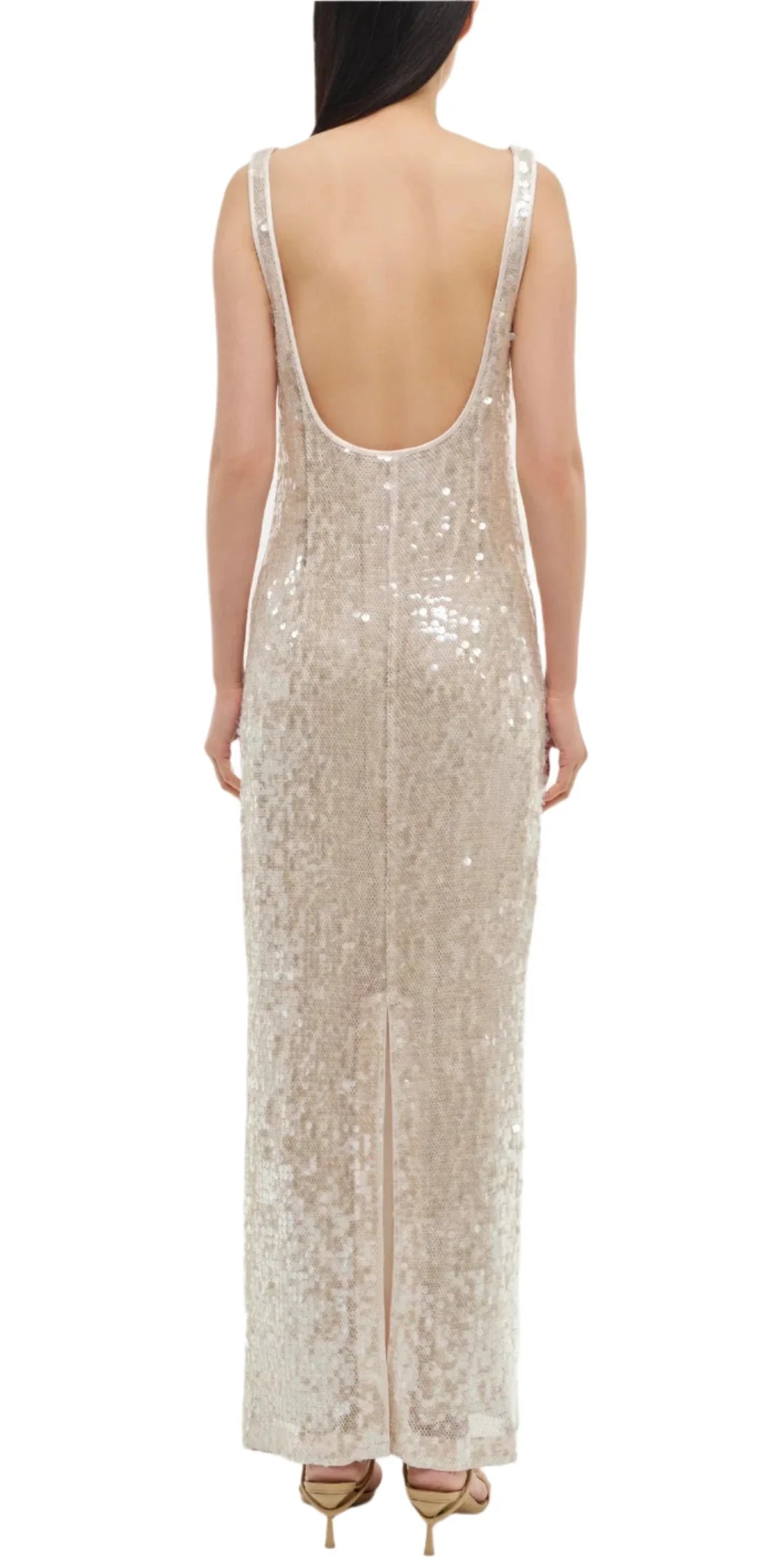 A person is seen from behind wearing the stunning Simkhai Bex Tank Maxi Dress in champagne, showcasing its sleeveless and backless design adorned with shimmering sequins cascading to a floor-length hem.