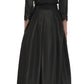 A person wearing a black, ankle-length, long-sleeve Simkhai Julip Belted Gown is shown from the back. The dress features tailored details with a fitted bodice and a flared skirt.