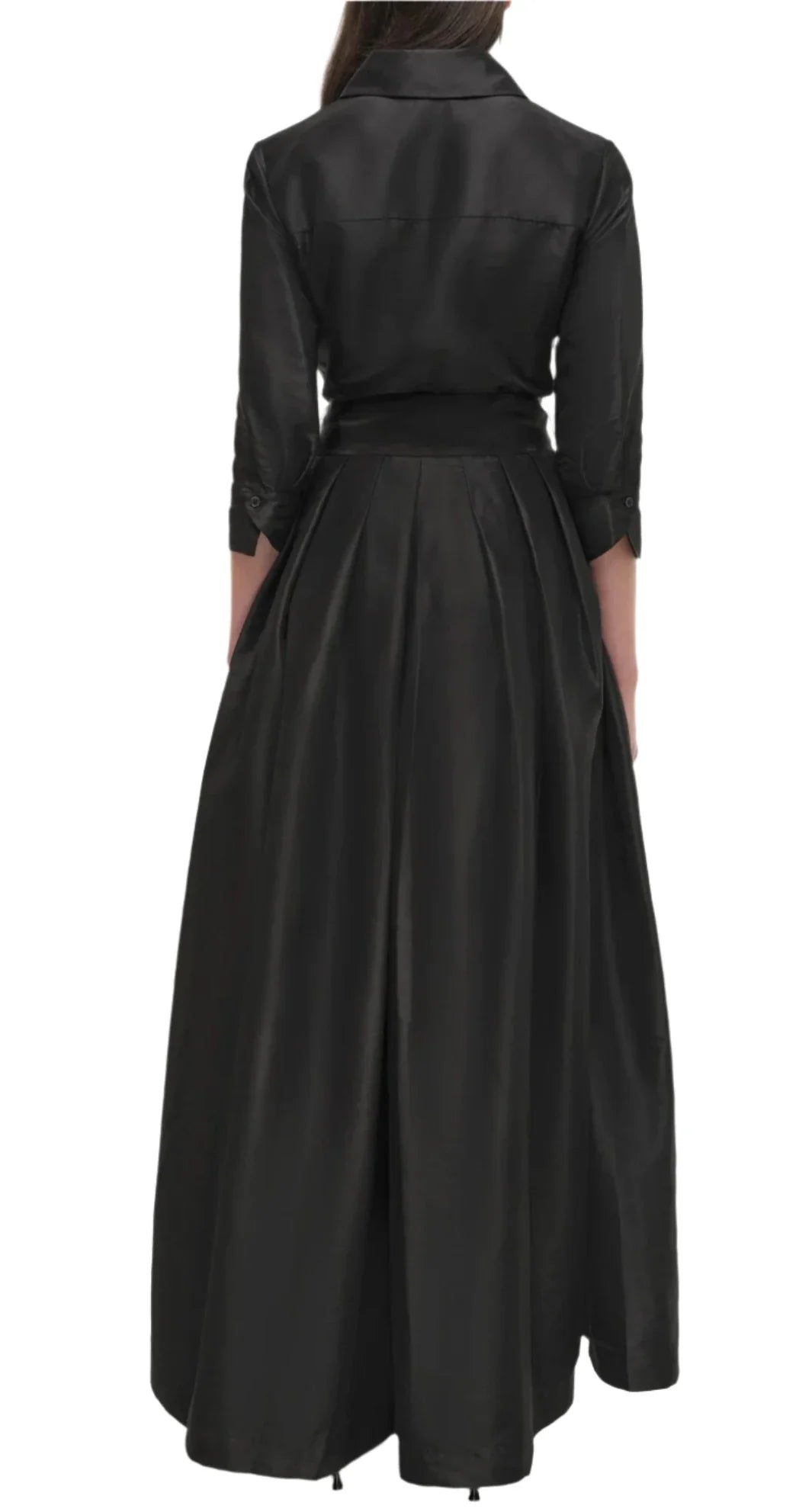 A person wearing a black, ankle-length, long-sleeve Simkhai Julip Belted Gown is shown from the back. The dress features tailored details with a fitted bodice and a flared skirt.