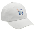 White Peter Millar Golf On The Rocks Performance Hat made from lightweight performance fabric, with a blue embroidered patch featuring a mountain and water design, displayed on a white background.