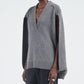 A person wears the Maria McManus Cocoon Cape, a gray V-neck alpaca-wool blend vest with wide arm openings, paired with black pants, against a plain background.
