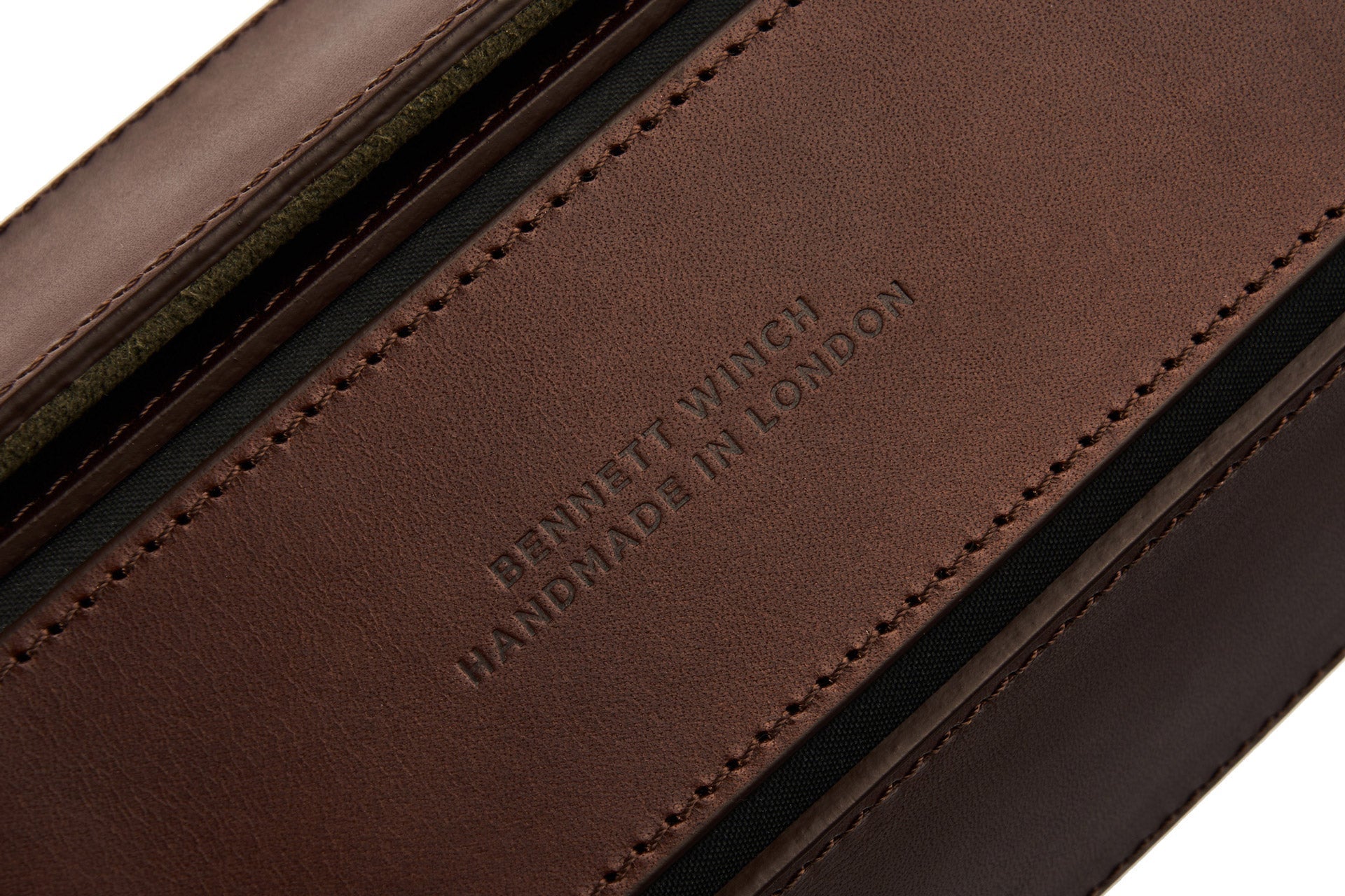 Close-up of a brown leather Bennett Winch Double Watch Roll with "handmade in London" embossed on it, showing detailed stitching and textures.