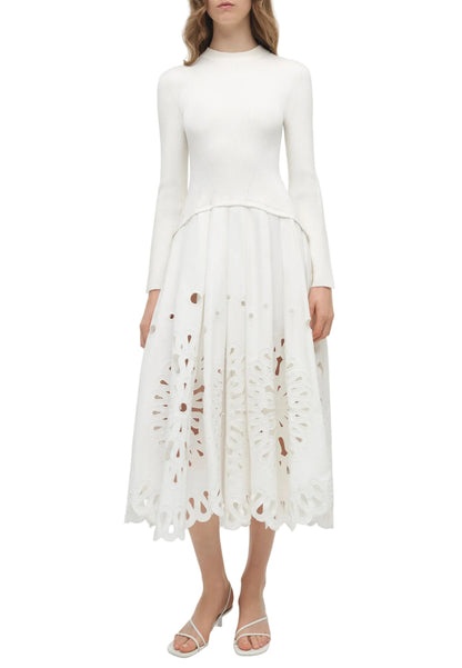 A woman wearing the Simkhai Daila Dress, featuring eyelet embroidery and a scalloped hem, paired with white sandals.