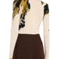 A rear view reveals someone in a luxurious Jason Wu Collection Merino Wool Crewneck Sweater, featuring abstract black, beige, and gold patterns, perfectly matched with high-waisted brown pants.