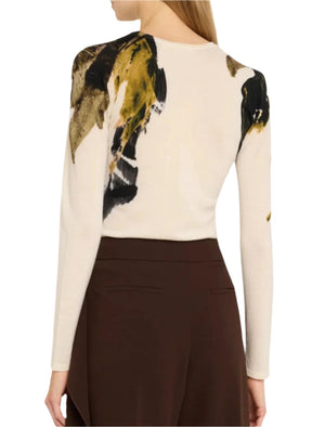 A rear view reveals someone in a luxurious Jason Wu Collection Merino Wool Crewneck Sweater, featuring abstract black, beige, and gold patterns, perfectly matched with high-waisted brown pants.