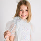 A young girl, dressed in a white, sparkly Snow Queen Tutu Dress from Tutu du Monde, smiles like an icicle princess against a plain light background as she holds the shimmering Snow Queen Wand and wears a matching crown.