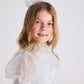 A young girl with long blonde hair is wearing a sparkling Tutu du Monde Snow Queen Tiara and a light blue, glittery princess dress, smiling at the camera against a plain white background.