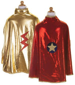 Two Great Pretenders Gold & Red Reversible Wonder Capes on display: one side features a gold cape with a red lightning bolt, while the other displays a bold red cape with a blue circle and yellow star emblem. Each reversible wonder cape is proudly made in Canada, offering vibrant superhero style for every young hero.