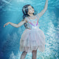 A young girl wearing the Tutu du Monde Girls’ Mermaid Magic Tutu Dress and a matching headband poses underwater, reaching upward toward the light as aquatic plants and sun rays shimmer around her.