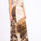 Woman wearing the Staud Phare Silk Maxi Dress, featuring a one-shoulder neckline and a landscape print of buildings and coastline, standing against a plain white background.