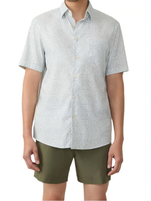 Wearing a Faherty Short-Sleeve Movement™ Monterey Shirt, person stands against a plain white background in an olive green shorts ensemble. The shirt is light-patterned and made from wrinkle-resistant Supima cotton.