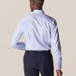 With their back turned and a hand on their hip, a person confidently wears an Eton Light Blue Signature Twill Shirt in Slim Fit. The dark trousers enhance the sleek, wrinkle-free appearance of the ensemble.