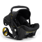The Doona Car Seat and Stroller, Midnight Edition, offers a stylish black design with an integrated stroller base, two yellow-trimmed wheels, and a canopy, perfectly blending style with functionality as the ultimate car seat stroller.