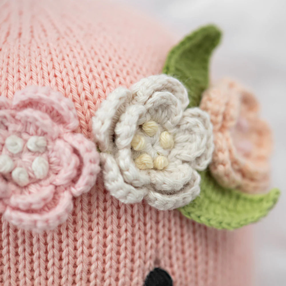 Close-up of Penelope the Flamingo - Regular 20" by Cuddle + Kind, featuring pink knit with tropical flowers and green leaves—ideal for celebrating #PenelopeBirthday in style.