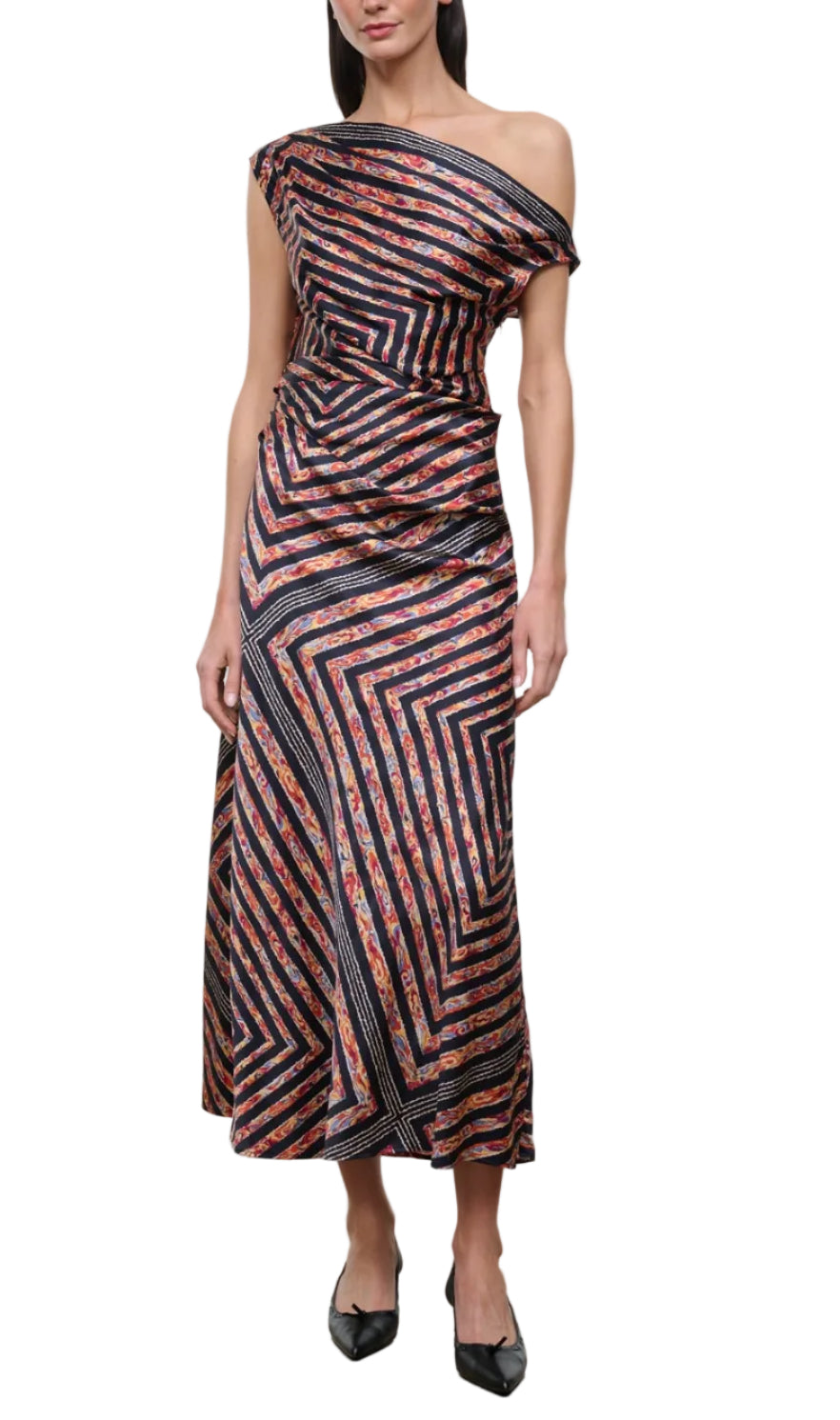 A woman wearing the Staud Portia Silk Studio Dress, an asymmetrical silk piece with a one-shoulder design, multicolored diagonal and geometric stripe patterns, and an adjustable tie detail, paired with black shoes.