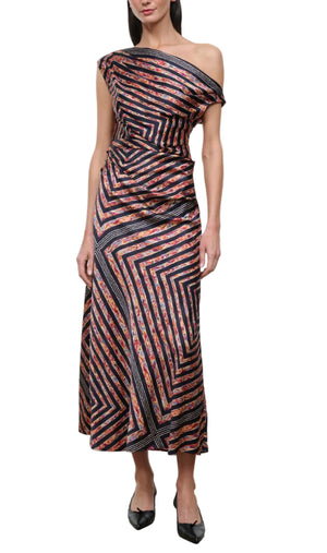 A woman wearing the Staud Portia Silk Studio Dress, an asymmetrical silk piece with a one-shoulder design, multicolored diagonal and geometric stripe patterns, and an adjustable tie detail, paired with black shoes.