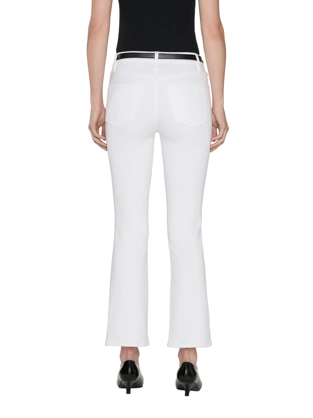 Model wearing The Reboot Crop by Frame—white ultra-stretch cropped bootcut jeans—paired with a black top and black heeled shoes, shown from the back.