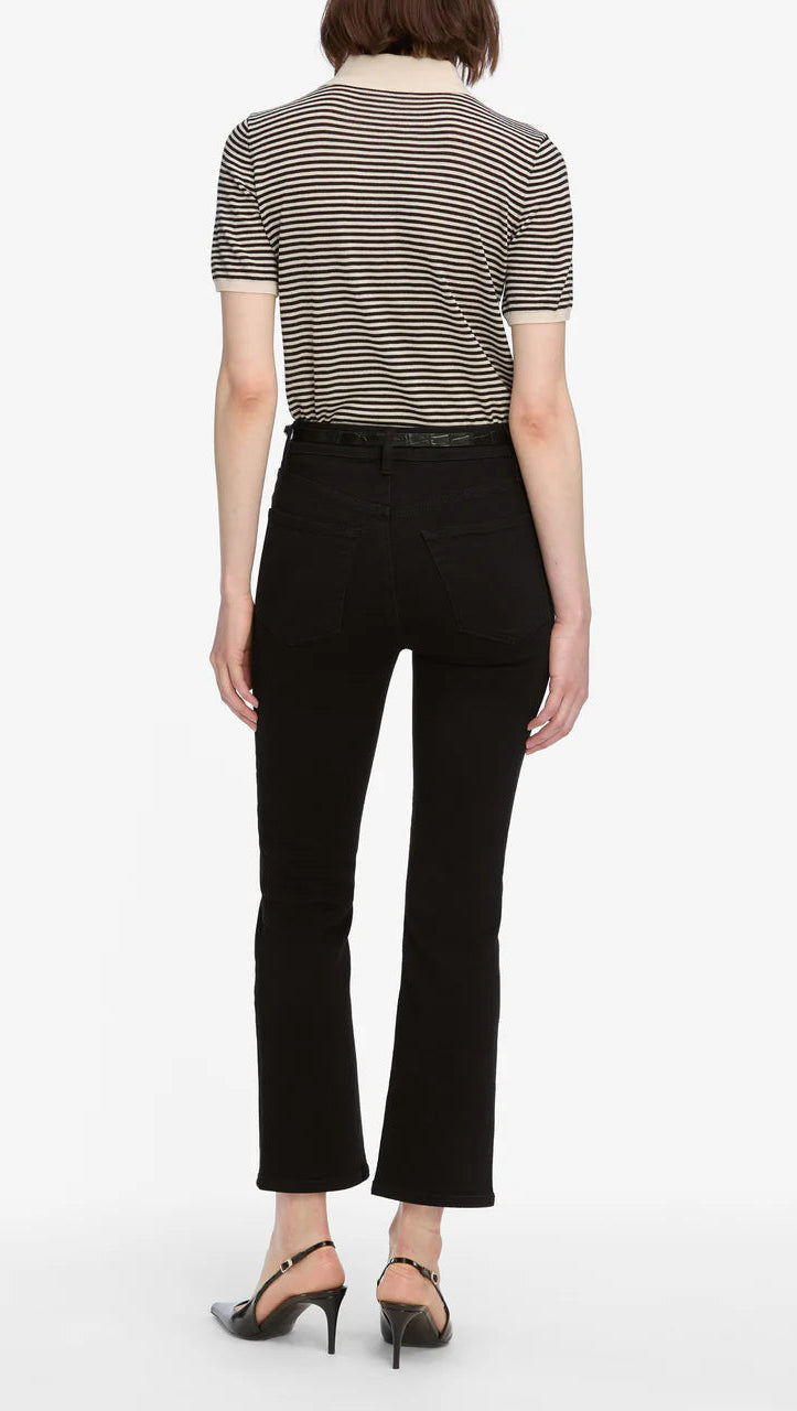 A person stands with their back to the camera, wearing a black and white striped short-sleeve shirt, FRAME’s The Reboot Crop jeans, crafted from an ultra-stretchy cotton blend, and black heeled shoes.