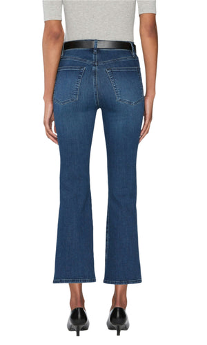 A person wearing a grey top, black heeled shoes, and Frame’s The Reboot Crop jeans in blue—featuring a cropped inseam and ultra-stretchy cotton blend—is seen from the back against a white background.