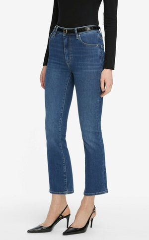 A person wearing a black long-sleeve top, The Reboot Crop blue ultra-stretchy cotton ankle-length jeans by Frame with a black belt, and black slingback heels.
