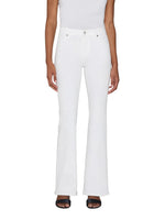 A person wearing The Icon white full-length flare jeans by Frame, a white sleeveless top, and black open-toe sandals, standing against a plain background.