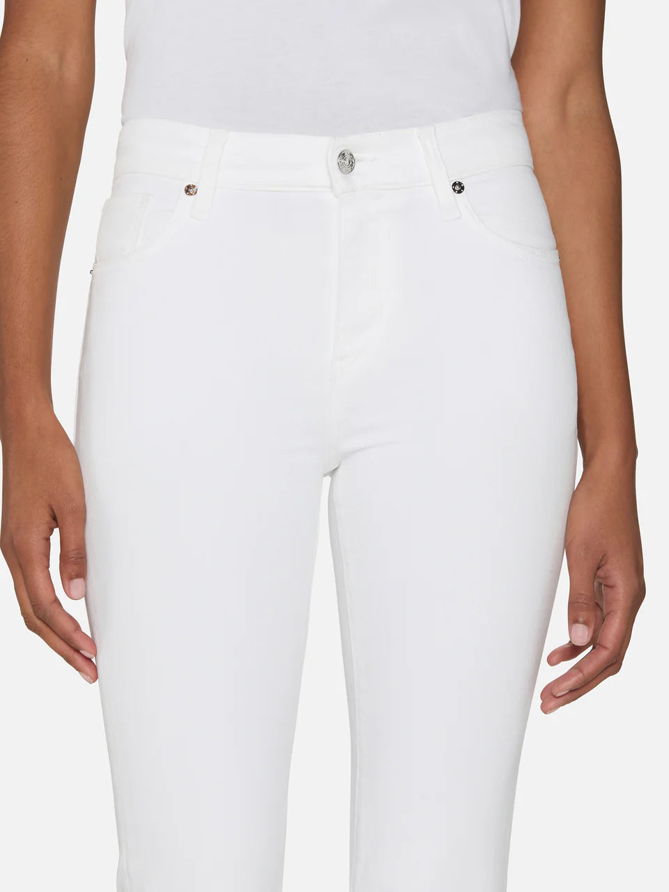 A model is shown from shoulders to mid-thigh, standing with arms relaxed at their sides against a plain background, wearing The Icon full-length flare white jeans by Frame and a white t-shirt.