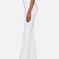 A person stands in profile against a plain background, wearing The Icon high-waisted flare jeans by Frame in white for a '70s-inspired silhouette, styled with a fitted white top and black open-toe heeled sandals.
