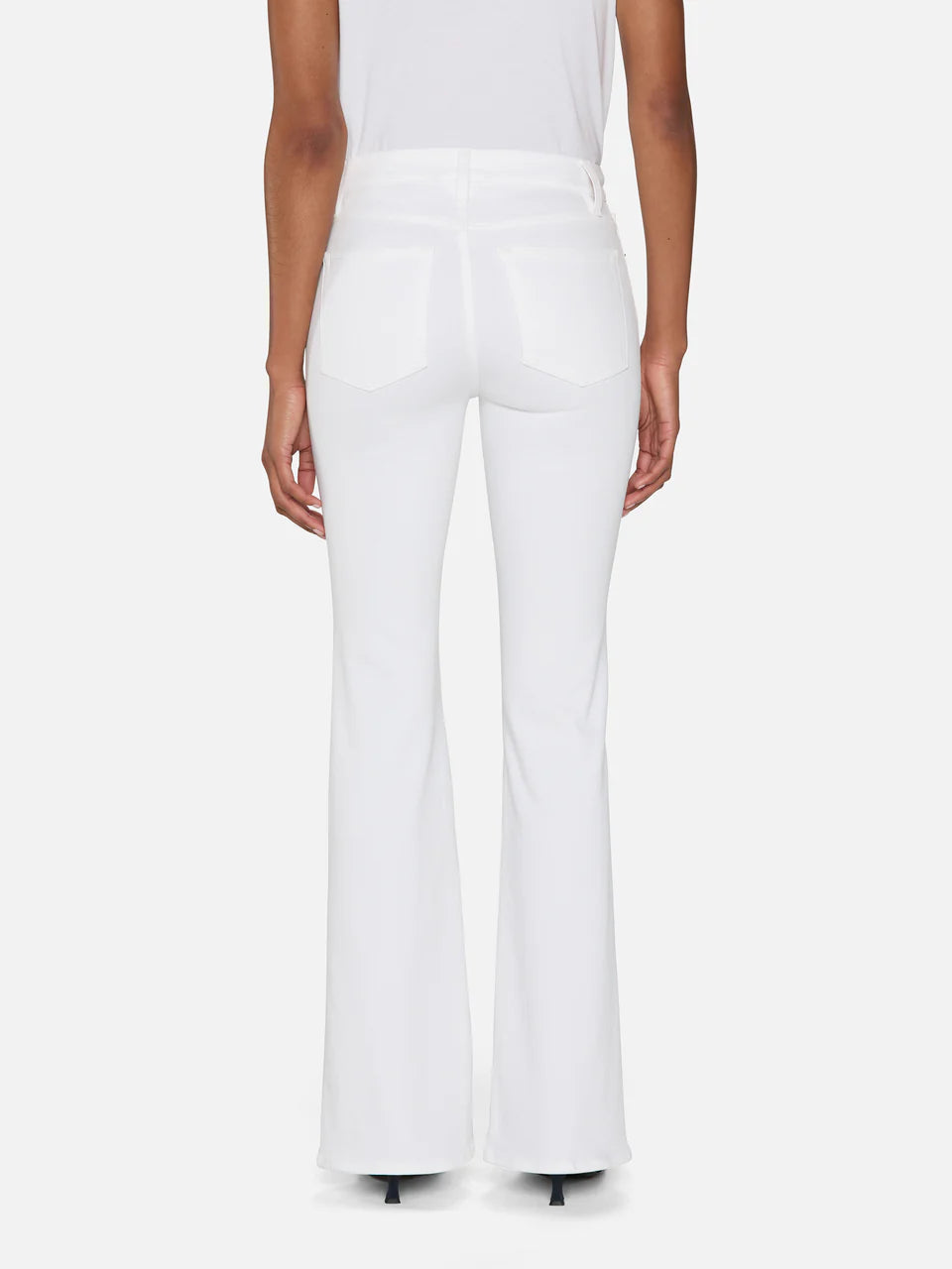 A person stands facing away against a plain background, wearing The Icon super-stretch flare jeans in white by Frame and a matching white top, with arms relaxed at their sides.