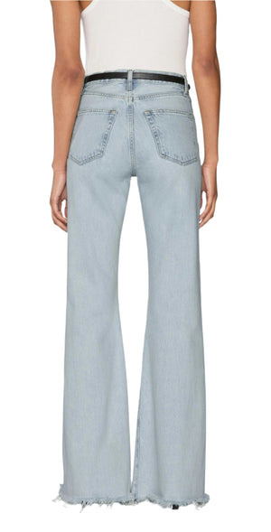Person wearing Frame’s The Lax light blue high-waisted, wide-leg flare jeans in rigid denim with frayed hems, styled with a black belt and white sleeveless top, photographed from the back for a vintage look.