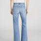 Model wears The Lax by Frame: a white short-sleeve blouse paired with high-waisted, light blue wide-leg flare jeans in classic rigid denim, shown from the back against a plain background for a vintage vibe.