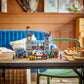 The Legos - Toyhouse LEGO® Creator™ 3-in-1 Medieval Horse Knight Castle set with figures and stalls is displayed on a wooden table in a cozy living room, featuring a blue sofa and decorative accents in the background.